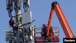 FILE - Workers install Verizon's 5G telecommunications equipment on a tower in Orem, Utah, U.S. December 3, 2019. (REUTERS/George Frey)