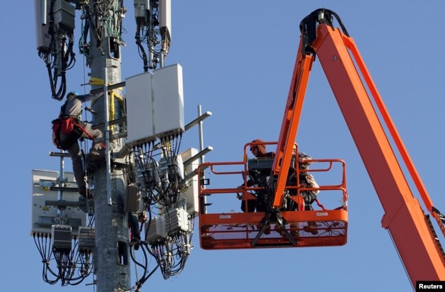 FILE - Workers install Verizon's 5G telecommunications equipment on a tower in Orem, Utah, U.S. December 3, 2019. (REUTERS/George Frey)