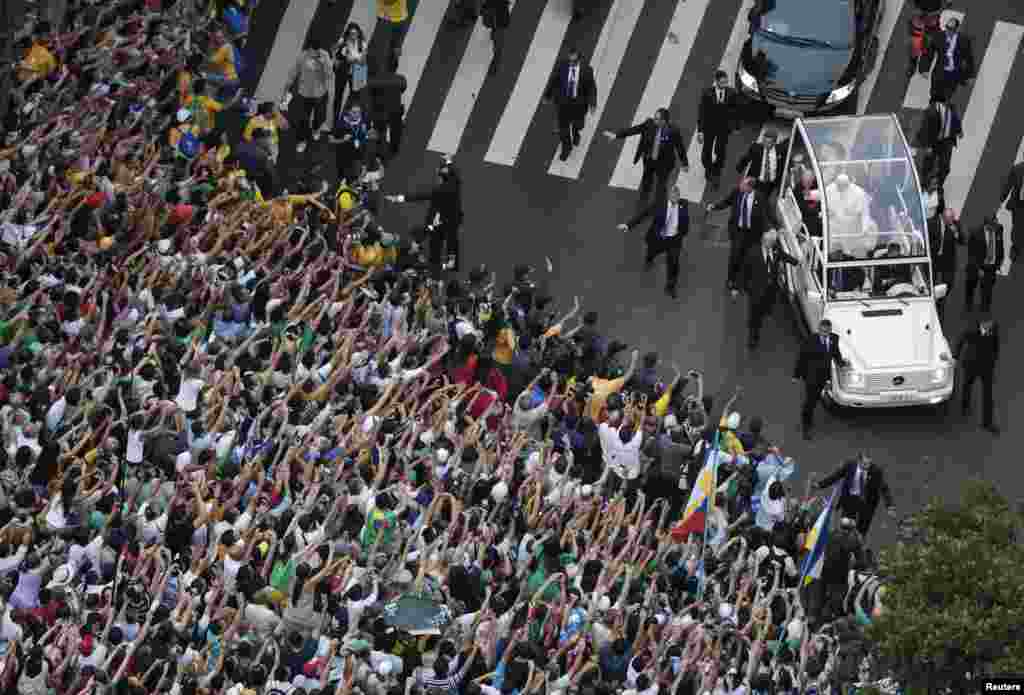 Paus Fransiskus menyapa umat dari mobilnya di pusat kota Rio de Janeiro (22/7).