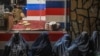 FILE - Afghan burqa-clad women sit in front of a bakery as they seek alms in Kabul, Jan. 6, 2022. 