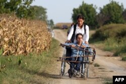 FILE - Nujeen Mustafa, refugee from Syria in a wheelchair moves toward the Croatian village of Tovarnik, close to the official Serbia-Croatia border, Sept. 16, 2015.