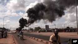 Tires burn in the background as people protest against the recent coup in Ouagadougou, Burkina Faso, Sept. 19, 2015. 
