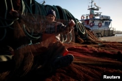 Fisherman Erbes Martins sews his net in the port of Peniche, Portugal, Feb. 6, 2018.