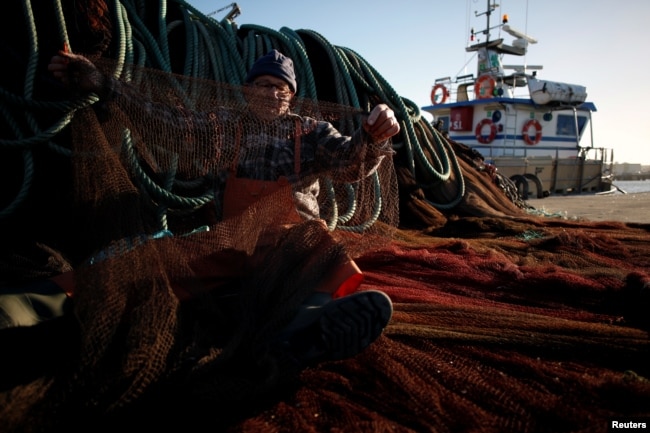 Fisherman Erbes Martins sews his net in the port of Peniche, Portugal, Feb. 6, 2018.