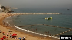 Des gens profitent de la plage alors que la police patrouillent, dans le détroit de Gibraltar, le 10 août 2015.