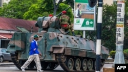 Un homme passe un char de l'armée zimbabwéenne où les soldats régulent le trafic routier, à Harare, au Zimbabwe, le 15 novembre 2017. 