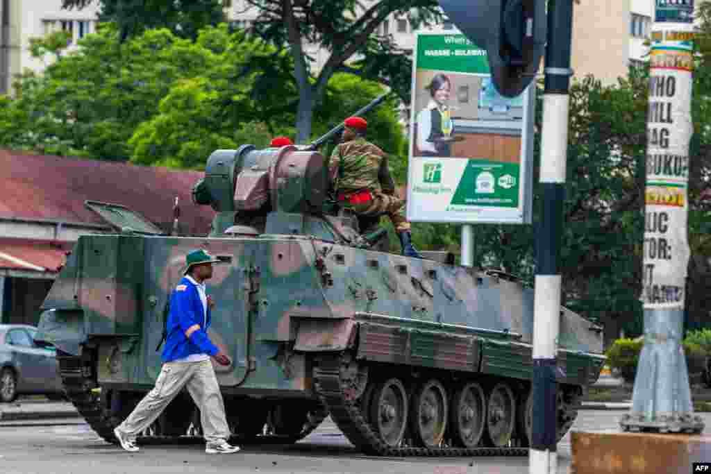 Un homme passe devant un char de l&#39;armée zimbabwéenne où les soldats régulent le trafic routier, à Harare, au Zimbabwe, le 15 novembre 2017.
