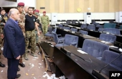 Iraqi Prime Minister Haider al-Abadi, left, looks at the damage after protesters stormed the Iraqi parliament building in Baghdad's fortified Green Zone area, May 1, 2016.