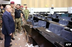 A handout image released by the press office of Iraqi Prime Minister Haider al-Abadi on May 1, 2016, shows him (L) looking at the damage after protesters stormed the Iraqi parliament building in Baghdad's fortified Green Zone area.