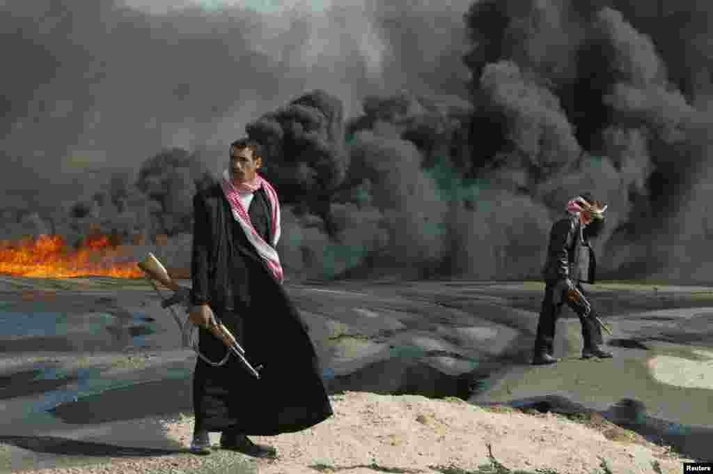 ماموران پلیس عراق از خط لوله ای در نزدیکی کربلا که آتش گرفته است، محافظت می کند. ٢٣ فوریه سال ٢٠٠٤.