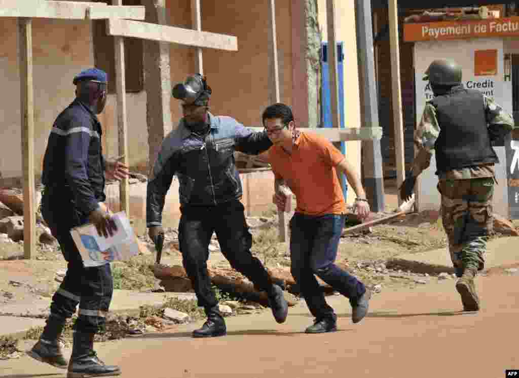 Security forces evacuate a man from an area surrounding the Radisson Blu hotel in Bamako, Mali. Gunmen went on a shooting rampage at the luxury hotel, seizing 170 guests and staff in an ongoing hostage-taking that has left at least three people dead.