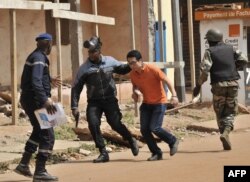 FILE - Malian security forces evacuate a man from an area surrounding the Radisson Blu hotel in Bamako, Nov. 20, 2015. Three Chinese railway executives were killed in the attack.Malian security forces evacuate a man from an area surrounding the Radisson Blu hotel in Bamako, Nov. 20, 2015.