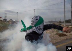 A Palestinian protester returns a teargas canister during clashes with Israeli troops following protests against U.S. President Donald Trump's decision to recognize Jerusalem as the capital of Israel, at the outskirts of the West Bank city of Bir Zeit.