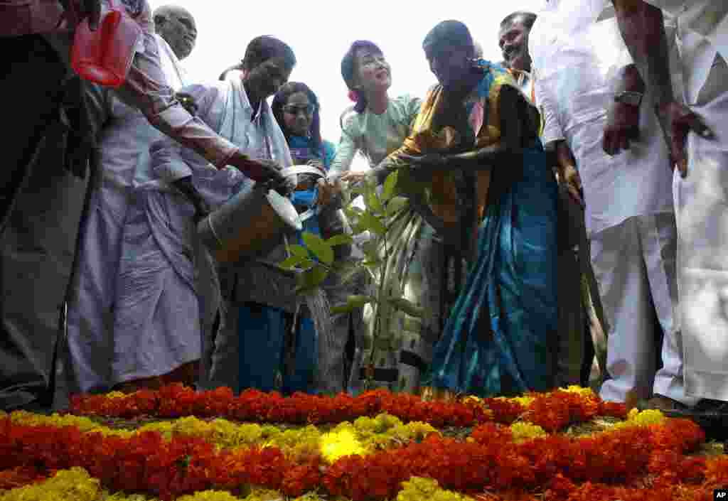 Burmese opposition leader Aung San Suu Kyi, center, waters a sapling after planting it in Govindapuram village, north of Bangalore, India, November 17, 2012. 