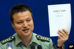 FILE - China's Defense Ministry spokesman Yang Yujun holds up a report on China's Military Strategy in Beijing, China, May 26, 2015. Yang criticized a U.S. report assessing China's island-building efforts in the South China Sea.
