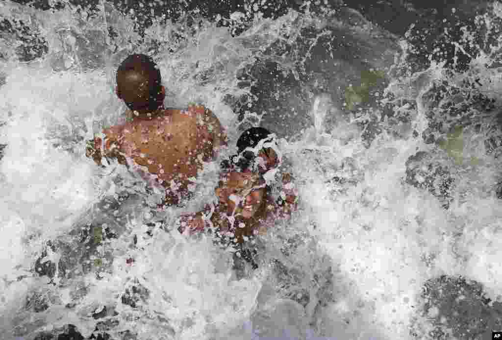 Waves hit people swimming in the polluted waters of Manila&#39;s bay, the Philippines as they celebrate Easter Sunday.