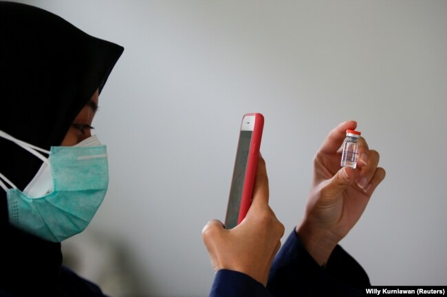 Seorang dokter mengambil gambar botol berisi vaksin Sinovac di fasilitas kesehatan kabupaten sebagai vaksinasi massal untuk Covid-19, di Jakarta, 19 Januari 2021. (Foto: Reuters/Willy Kurniawan)