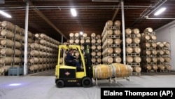 In this photo taken Thursday, Nov. 21, 2019, barrels of wine are moved into storage at Chateau Ste. Michelle winery in Woodinville, Washington.