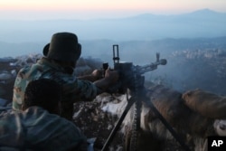 Syrian army personnel, backed by Russian airstrikes, fires machine gun in Latakia province, near border with Turkey, Oct. 10, 2015.