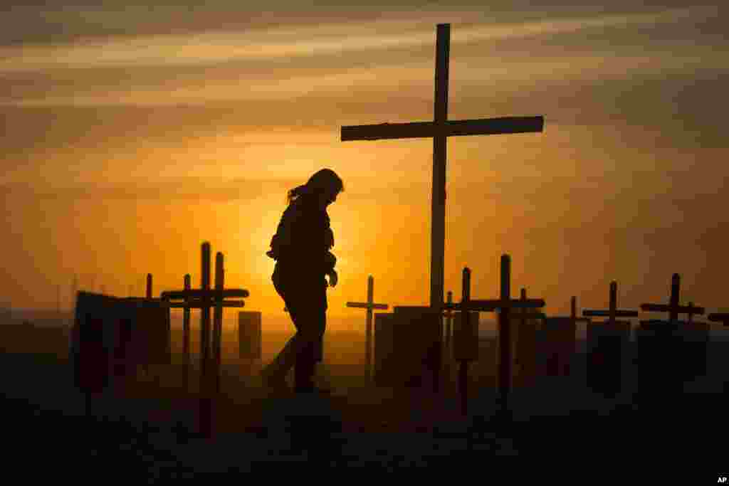 A police officer walks among 152 black wooden crosses placed on Copacabana beach, in Rio de Janeiro, Brazil, by the NGO Rio de Paz in memory of police officers killed in Rio de Janeiro state between 2013 and 2014. 