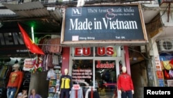 FILE - Vendors sit outside a shop selling clothes in Hanoi, Vietnam, October 3, 2014.