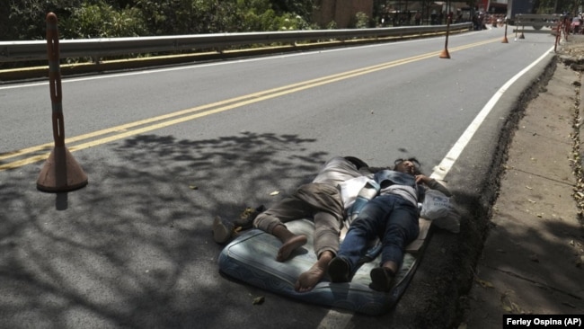 Venezuelan migrants sleep on a mattress on the side of the highway in Pamplona, Colombia, Wednesday, Oct. 7, 2020,(AP Photo/Ferley Ospina)