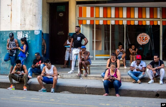 In this Jan. 6, 2017 photo, people use a public wifi hotspot in Havana, Cuba. Home internet came to Cuba in December 2016, in a limited pilot program