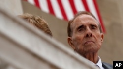 FILE - Former Sen. Bob Dole watches as President Donald Trump speaks during a Memorial Day ceremony at Arlington National Cemetery, May 29, 2017, in Arlington, Virginia.