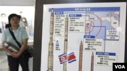 Seorang warga Seoul berdiri di dekat gambar senjata-senjata misil Korea Utara.