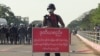 FILE - Policeman stands behind a banner reading "if this line is crossed, Myanmar police force will fire with live ammunition" during a protest against the military coup and to demand the release of Aung San Suu Kyi, in Naypyitaw, Myanmar, February 8, 2021.