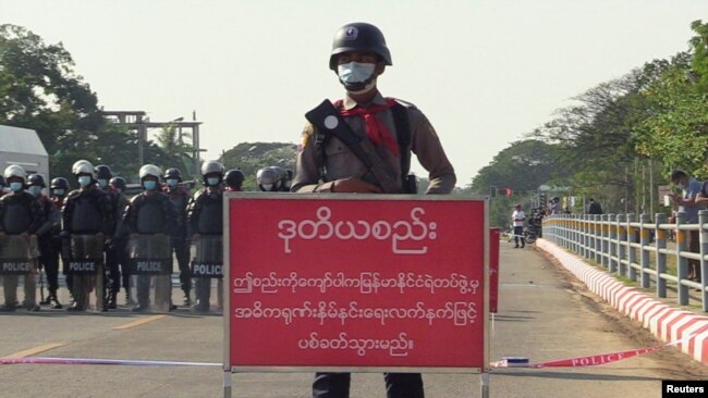 FILE - Policeman stands behind a banner reading