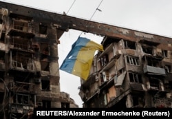 우크라이나 남동부 항구도시 마리우폴 시내 파괴된 아파트 단지 안에서 지난 14일 훼손된 우크라이나 국기가 바람에 날리고 있다.