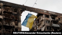 Ukrajinska zastava kod uništene stambene zgrade u Mariupolju (Foto: REUTERS/Alexander Ermochenko)