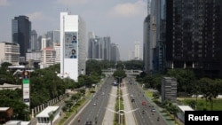 Kendaraan bergerak di jalan utama dekat papan reklame dengan kampanye kesadaran masker ganda, di Kawasan Pusat Bisnis Sudirman (SCBD), di tengah pandemi COVID-19 di Jakarta, 26 Juli 2021. (REUTERS/Willy Kurniawan)
