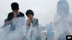 People pray for the atomic bomb victims at the Hiroshima Peace Memorial Park in Hiroshima, western Japan, Aug. 6, 2013. 