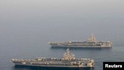 FILE - The U.S. Navy aircraft carrier USS Carl Vinson (CVN 70), bottom, is seen relieving the USS George H.W. Bush in the Arabian Gulf Oct. 18, 2014.