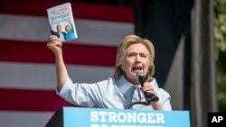 Calon presiden AS dari Partai Demokrat Hillary Clinton memegang buku berjudul "Stronger Together" saat berbicara dalam festival Hari Buruh di Cleveland, Ohio (5/9). (AP/Andrew Harnik)