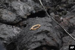 An item sits on a cooled lava flow in the Leilani Estates subdivision near Pahoa, Hawaii, May 8, 2018. Scientists confirm that volcanic activity has paused at all 12 fissures that opened up in a Hawaii community and oozed lava that burned 35 structures.