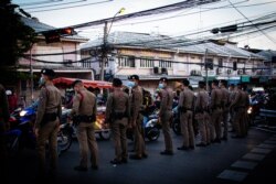 Thai police officers look on as anti-government protests walk through the streets of Bangkok, May 2021.