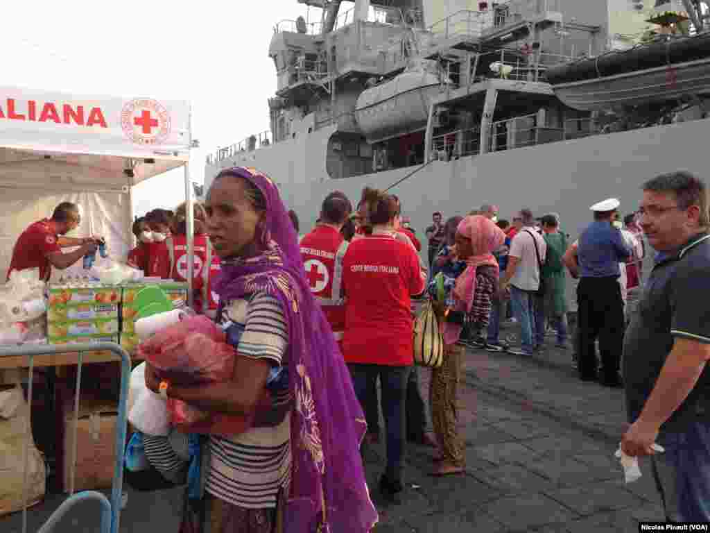 Para migran menerima makanan dari para petugas Palang Merah di Catania.