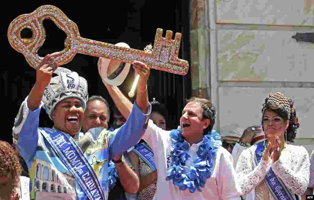 Walikota Rio de Janeiro&nbsp; Eduardo Paes (kedua dari kanan)&nbsp; menyerahkan kunci kota kepada Rei Momo, atau Raja Karnaval Wilson Neto (kiri) di Istana Cidade di Rio de Janeiro, Brasil. Acara itu secara resmi membuka pekan Karnaval 2015 di Rio. &nbsp;