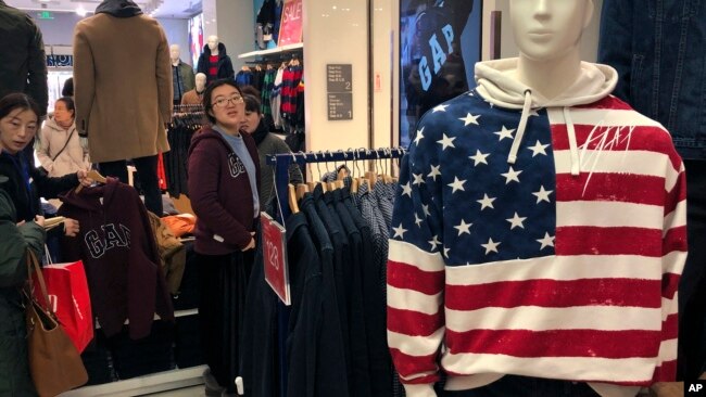 一名女子在美国零售商Gap北京旗舰店试穿毛衣。中美贸易谈判的不确定性给亚洲市场蒙上了一层阴影,双方都对未来保持沉默。(2019年1月10日)