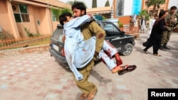An injured man is carried to a hospital after a car bomb in Jalalabad city, Afghanistan, June 17, 2018.