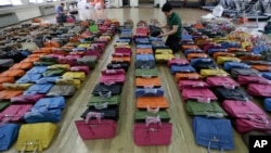 A police official checks some 400 counterfeit bags at the Jungbu police station in Seoul, South Korea, June 1, 2016. 