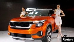 Models pose alongside the Kia SP SUV Concept car after its launch at India Auto Show 2018 in Greater Noida, India