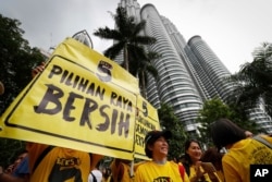 Activists from the Coalition for Clean and Fair Elections (BERSIH) show a placard reading "Clean Election BERSIH" in front of the Petronas Towers during a rally in Kuala Lumpur, Malaysia Saturday, Nov. 19, 2016.