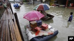 Residents use makeshift floats as others cross a makeshift bridge built over a flooded road in suburban Pasig, east of Manila, Philippines, August 15, 2012.