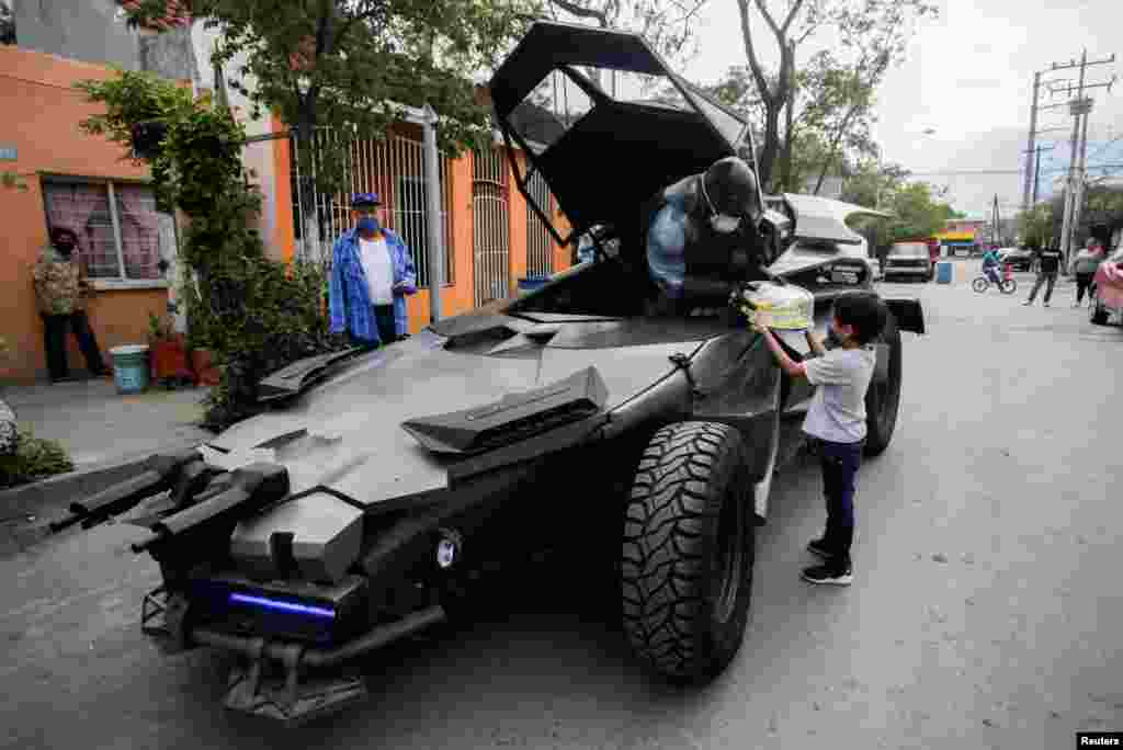 Mexican lawyer Candelario Maldonado dressed as the fictional character Batman, gives a birthday cake to a child in Monterrey, Mexico, April 18, 2020.