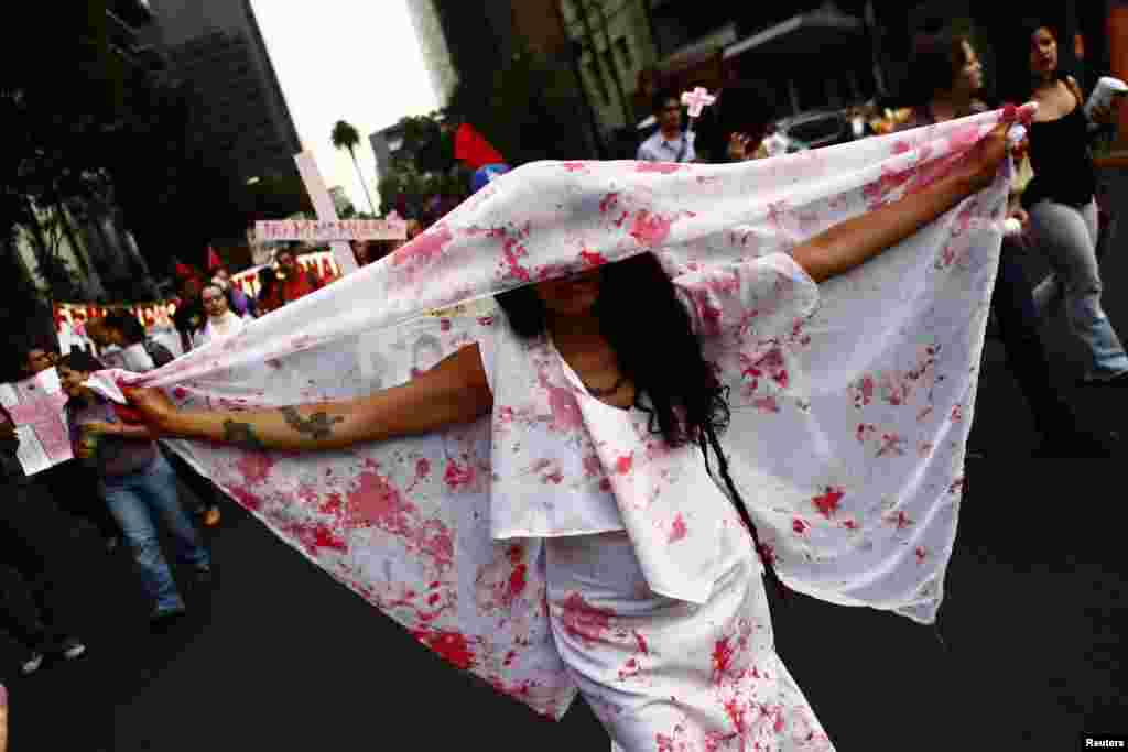 A woman holds a sheet with stains to represent blood during a demonstration to demand justice for women, who are the victims of violence, in Mexico City, Mexico, Mar. 8, 2013. 