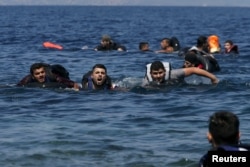 Di dân và người tị nạn Syria và Iraq bơi về phía bờ khi chiếc thuyền của họ bị xì hơi cách đảo Lesbos của Hy Lạp 100 mét, ngày 13 tháng 9, 2015.